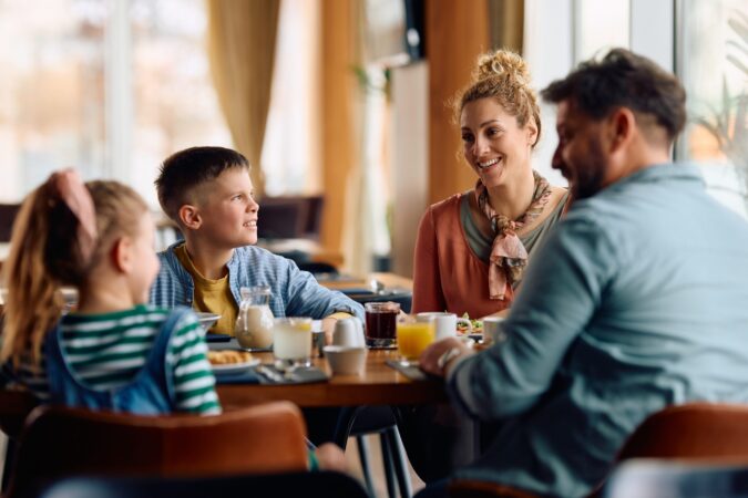 Happy,Family,Communicating,While,Eating,Breakfast,At,Dining,Table,In